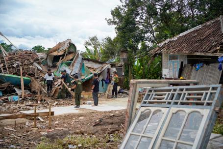 People examine earthquake damage to homes in Indonesia.